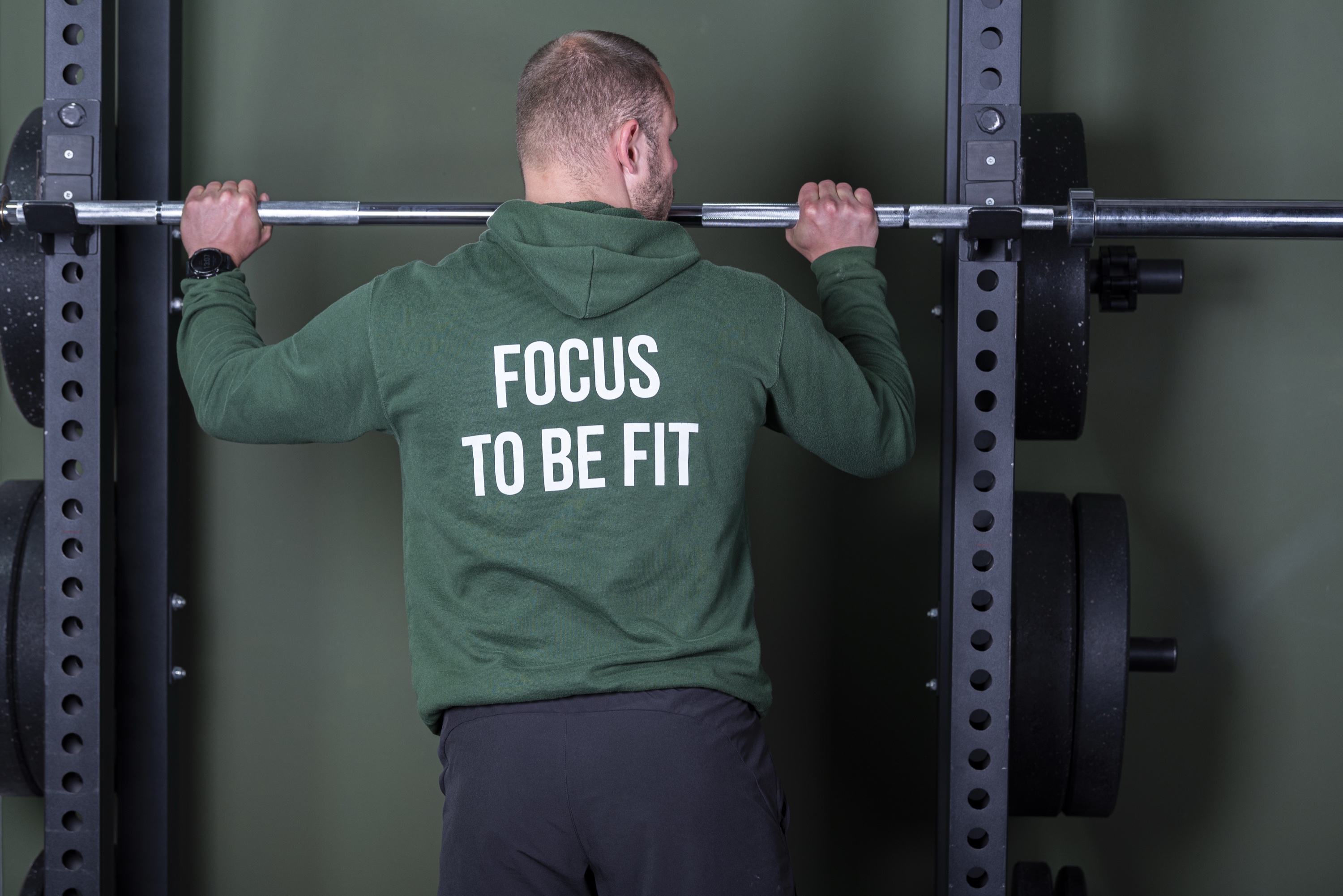 Trainer in Focus to be Fit-kleding staat met een halter in de trainingsruimte