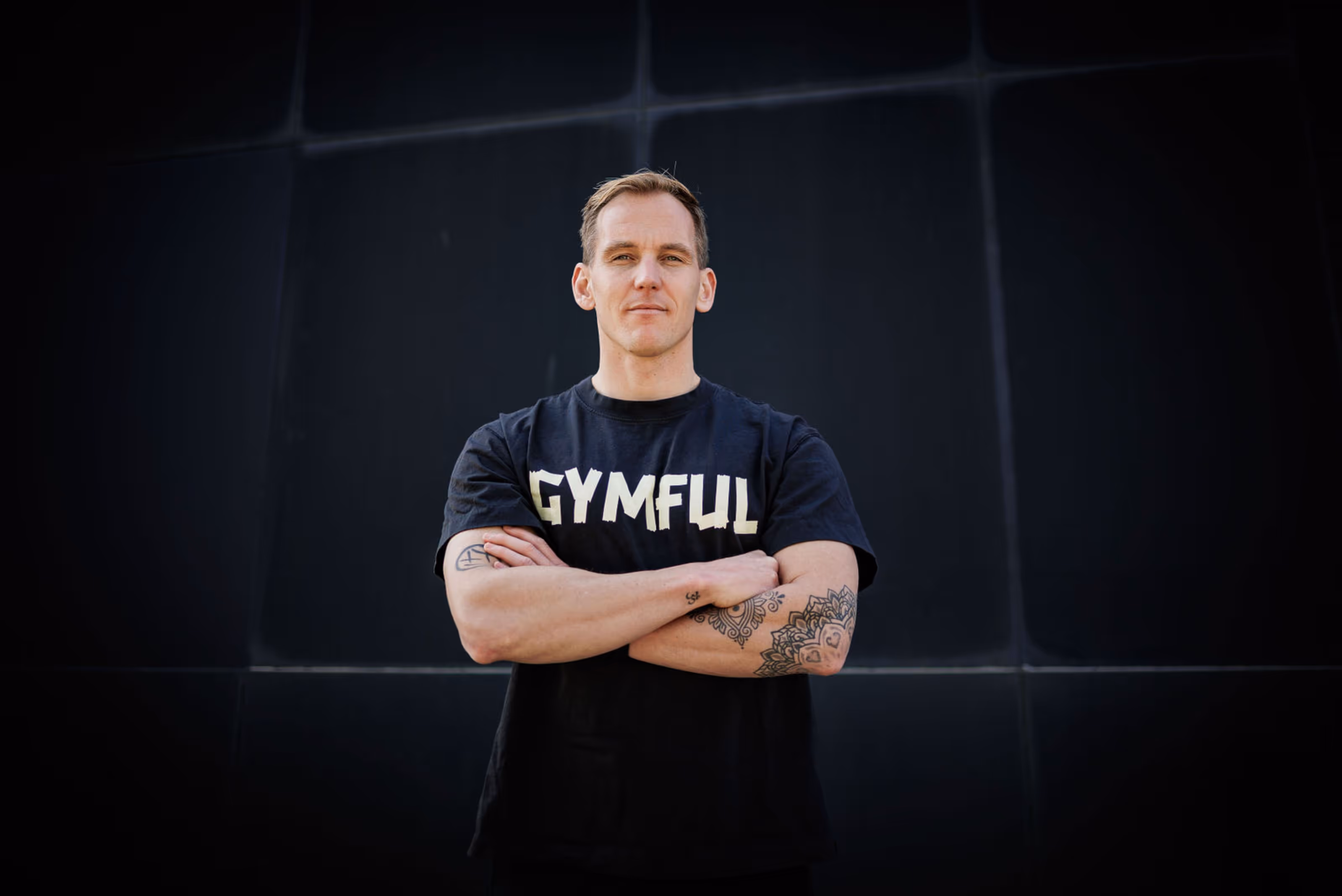 Sebastian Smeenk, eigenaar van Gymful, voor een zwarte achtergrond in een Gymful T-shirt