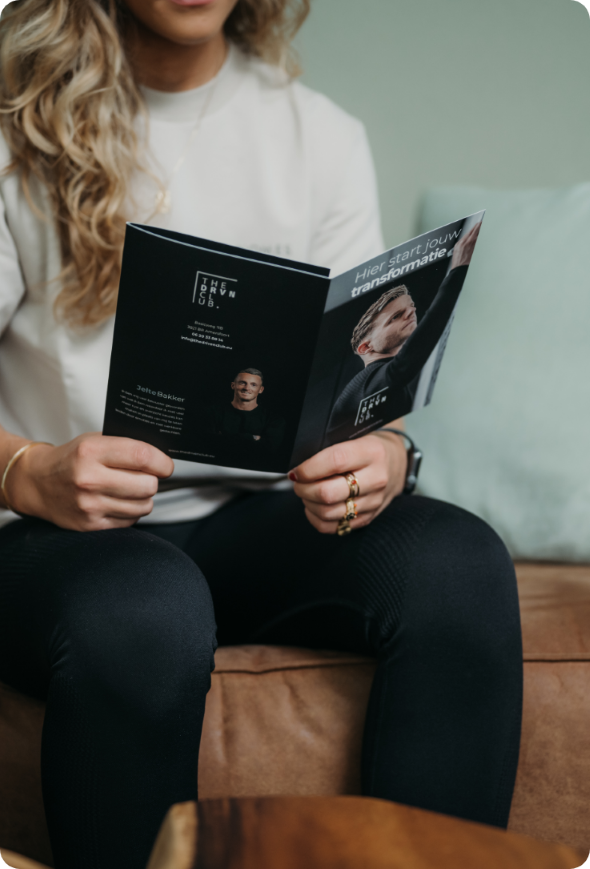 Brochure van The Driven Club in handen van een lezer