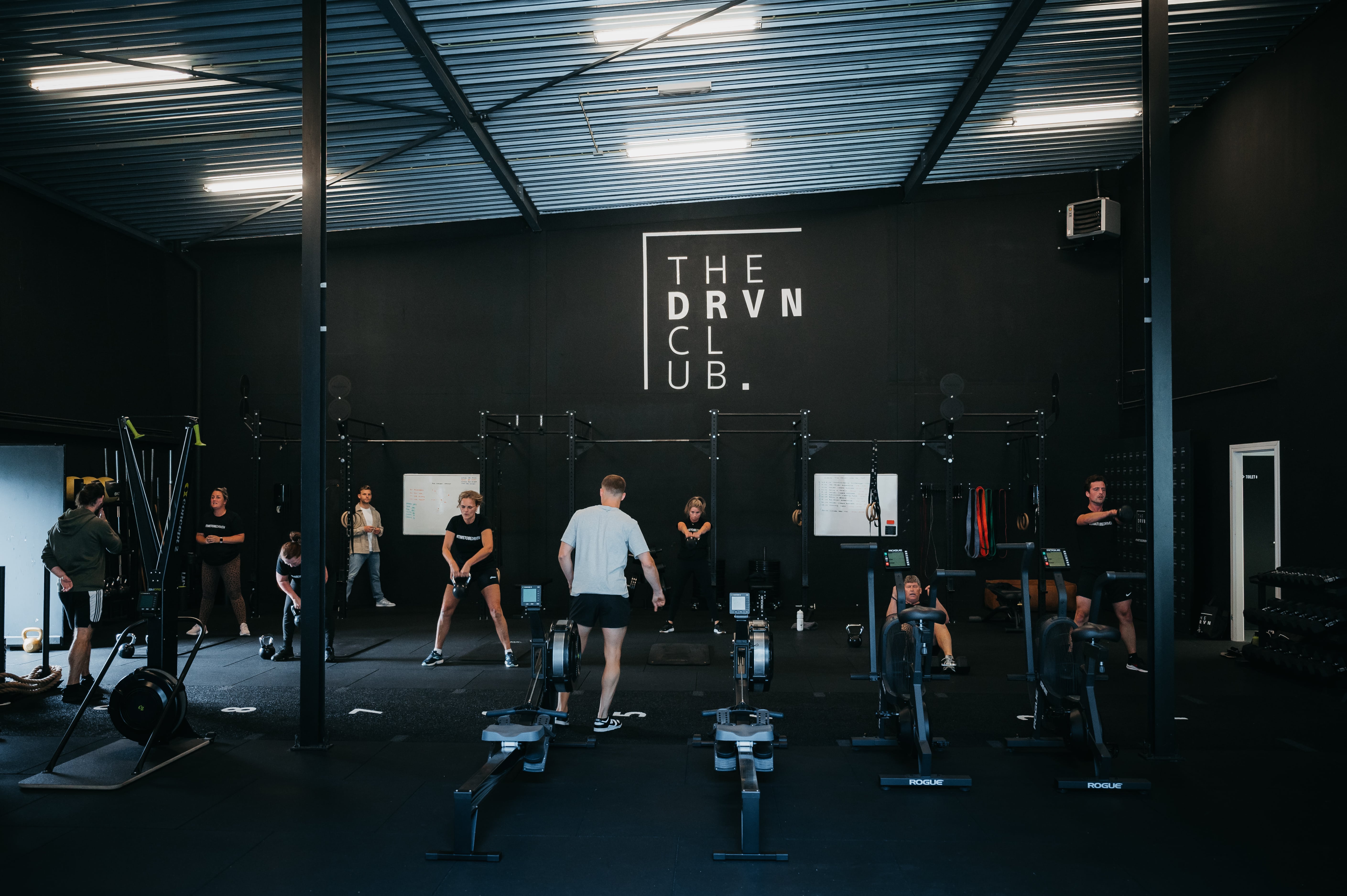 Sporters trainen in de ruimte van The Driven Club, met het clublogo op de achterwand